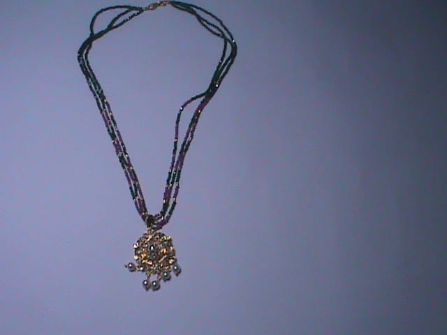 Black beaded necklace with golden pendant and pearl accents