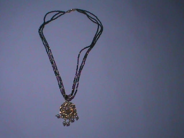 Black beaded necklace with golden pendant and pearl accents