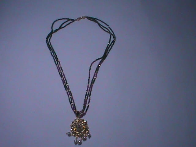 Black beaded necklace with golden pendant and pearl accents