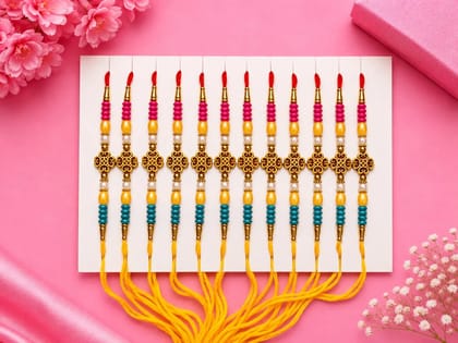 Celebrate Raksha Bandhan with this elegant set of 12 lotus design rakhis. Featuring pearl-like beads, yellow accents, and red-yellow threads for a festive traditional look.
