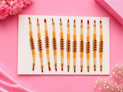Celebrate Raksha Bandhan with this elegant set of 12 lotus design rakhis. Featuring pearl-like beads, yellow accents, and red-yellow threads for a festive traditional look.