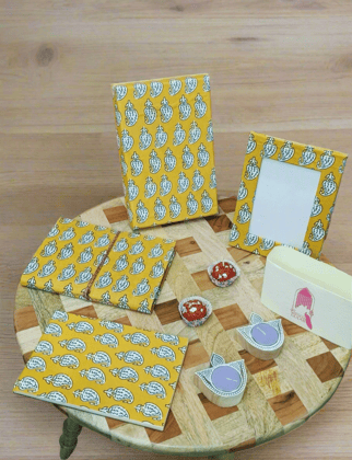 Gift Box with Work Desk Essential : 1 Diary, 1 Notepad, 1 Photoframe, 2 laddoo candles, 2 handblock candles-1 Diary, 1 Notepad, 1 Frame, 4 Candles